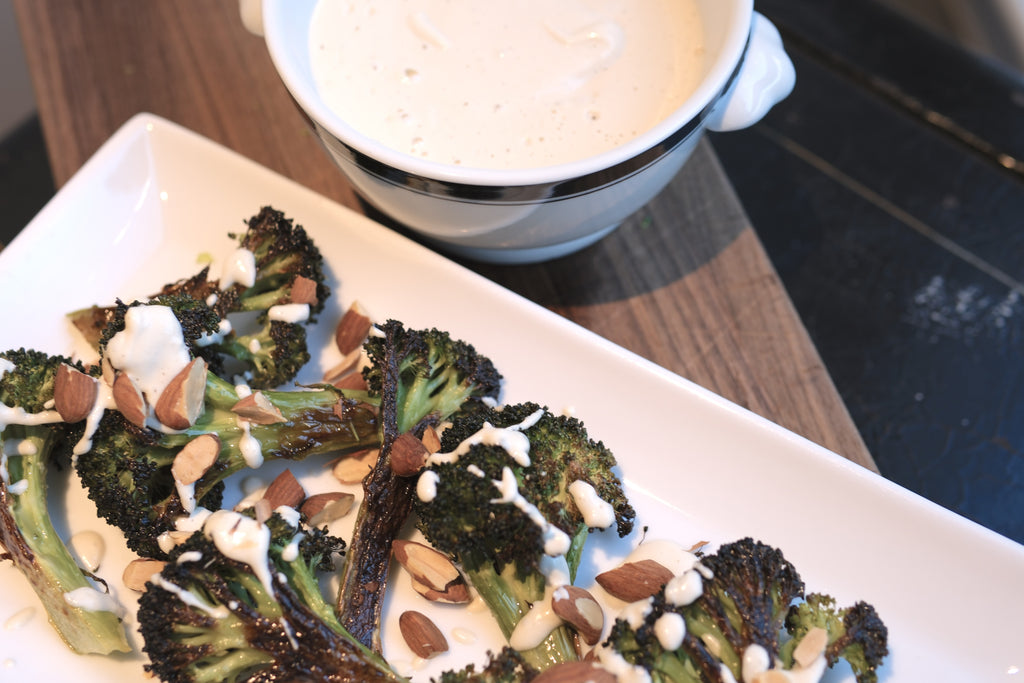 Roasted broccoli with Garlic Cashew Cream Sauce on a white serving plate