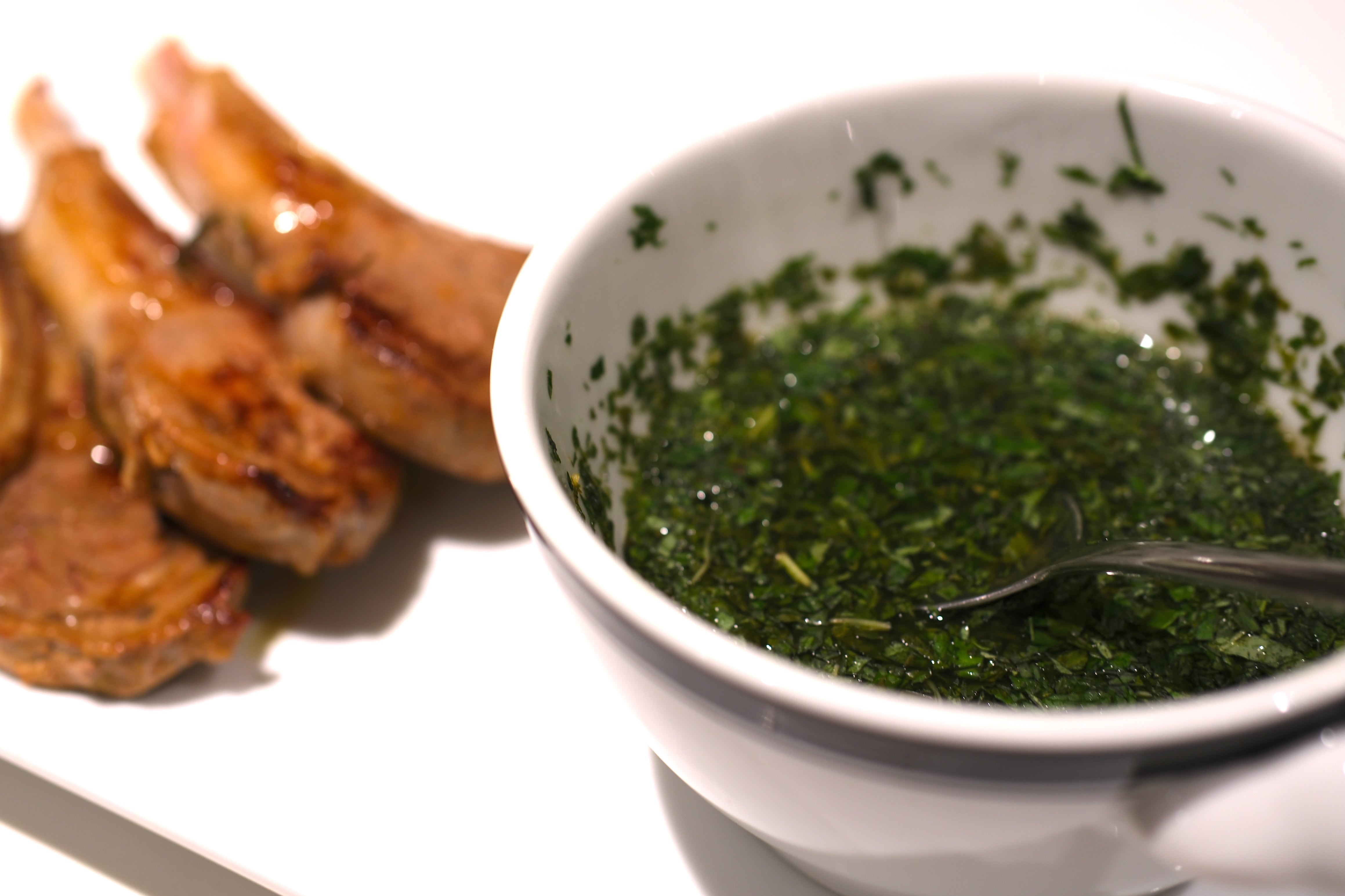 Mint sauce in bowl with lamb chops in background